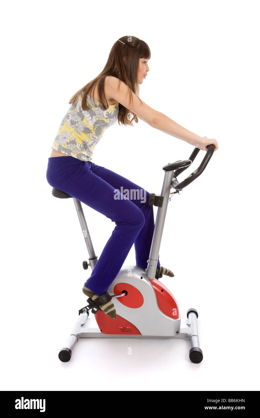 Ragazza adolescente facendo fitness su una bicicletta stazionaria Foto Stock