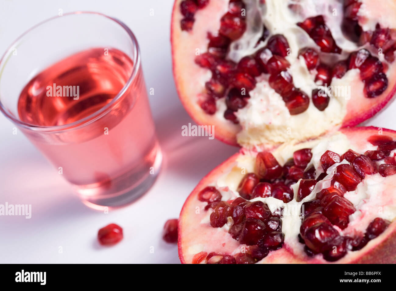 Pmegranate tagliato a metà su sfondo bianco e il bicchiere di succo di frutta Foto Stock