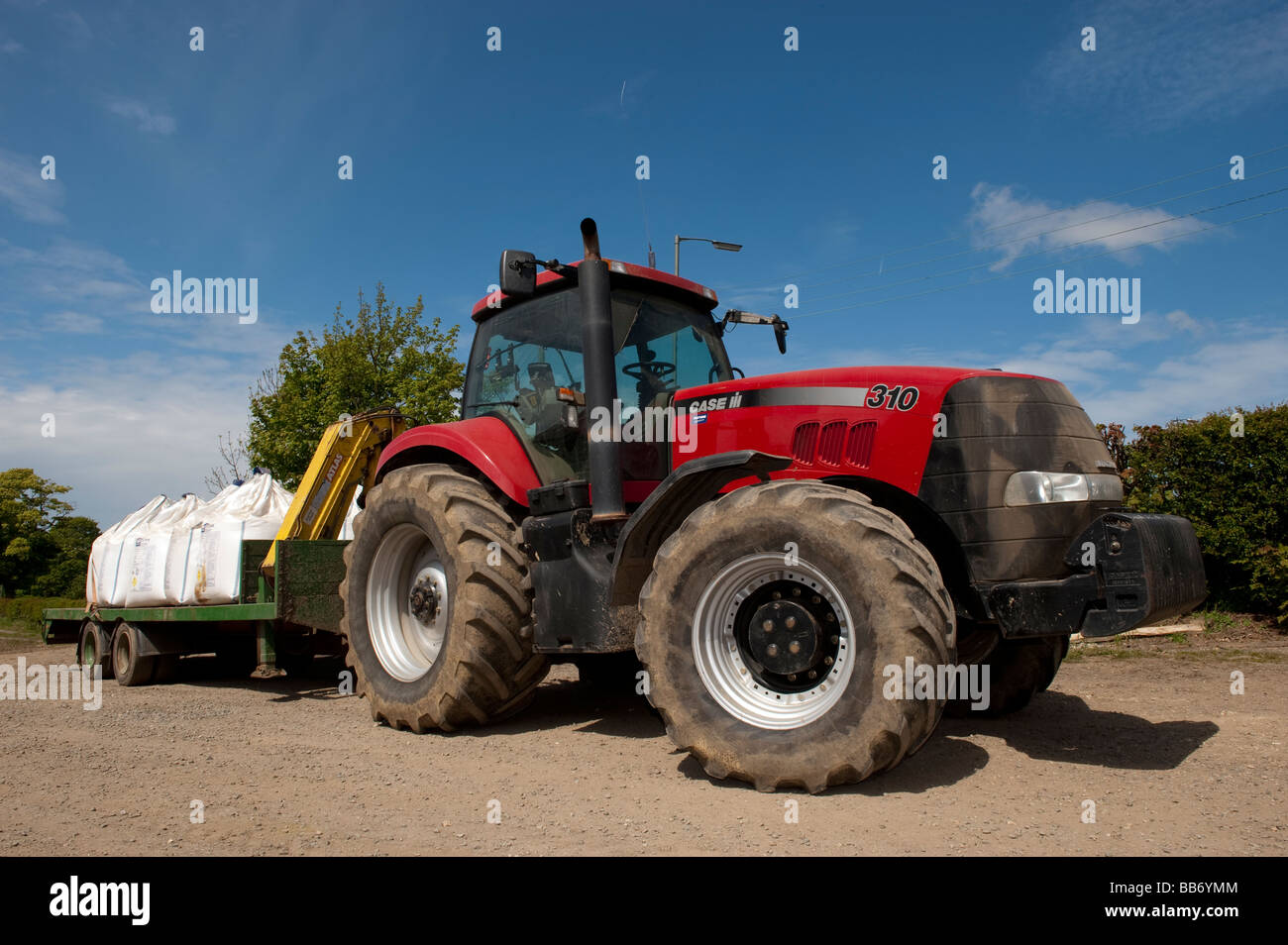 Case IH 310 il trattore con il rimorchio caricato con allegata di fertilizzanti Foto Stock