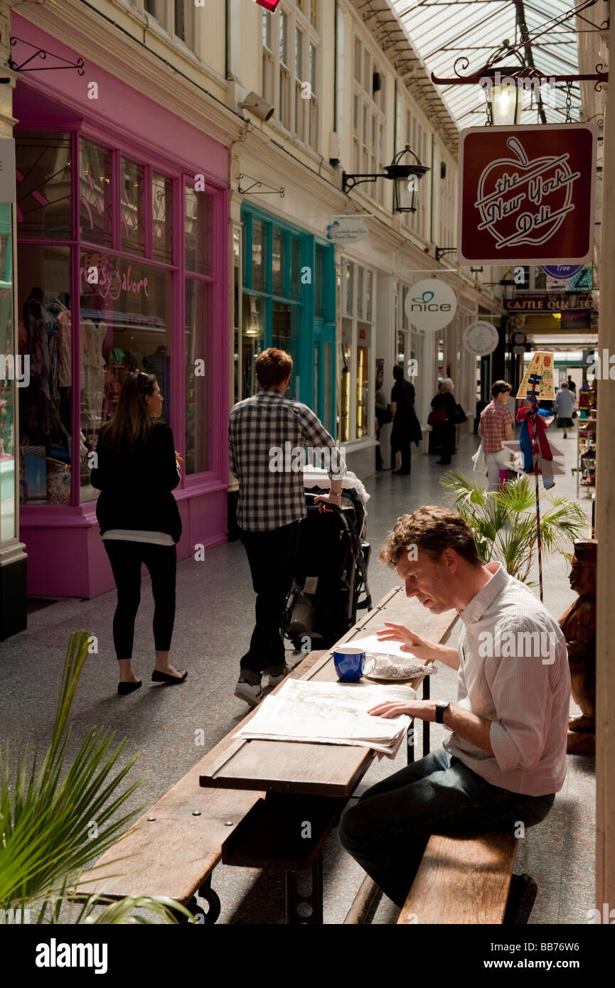 Un uomo seduto al di fuori della New York Deli Cafe in castello Arcade centro di Cardiff Wales UK Foto Stock