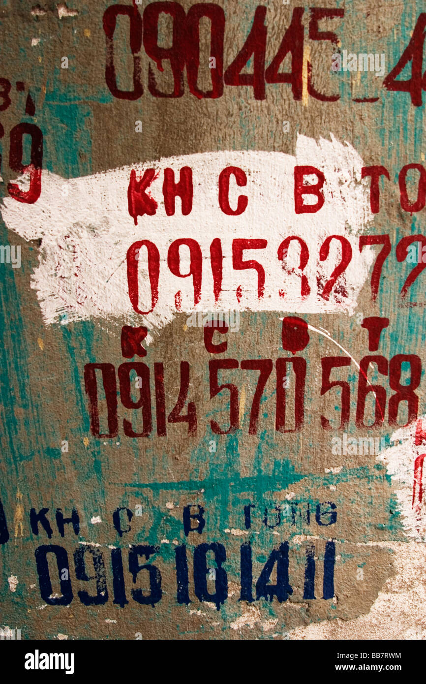 I numeri di telefono di area residenze e le aziende sono stampata su una parete nel centro di Hanoi, Repubblica Socialista del Vietnam. Foto Stock