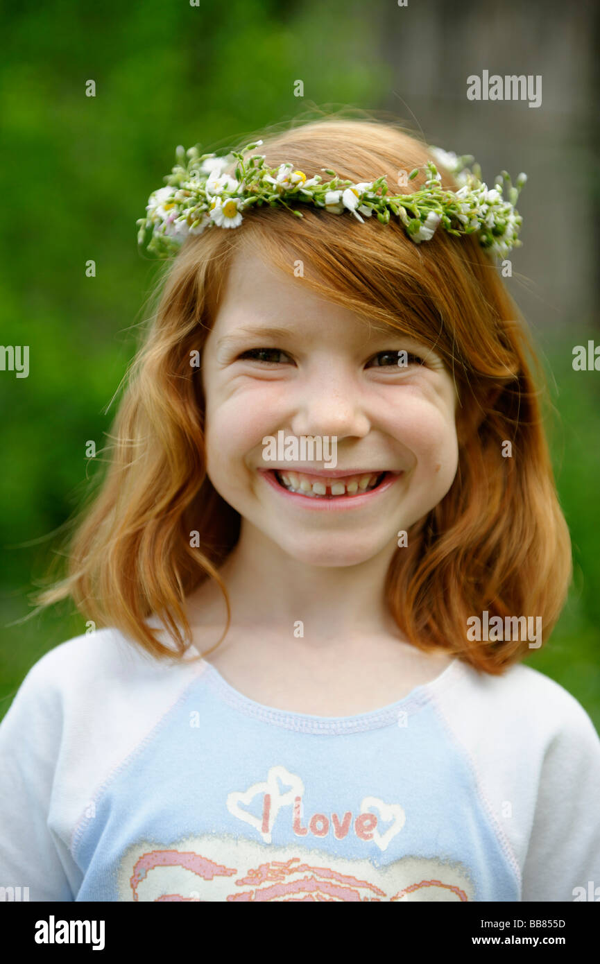Giovane ragazza che indossa una corona di fiori tra i capelli Foto Stock