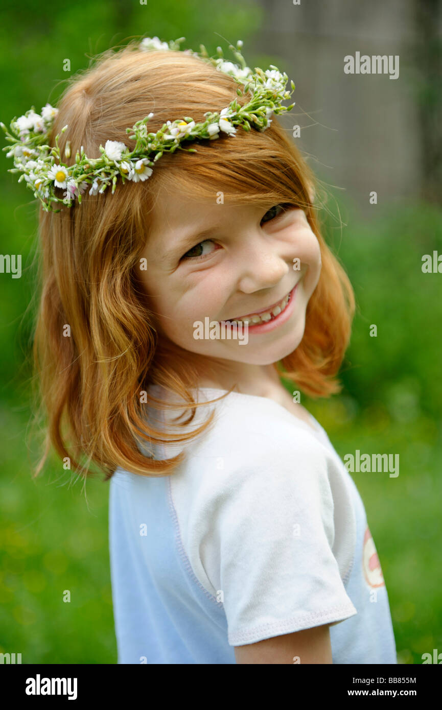 Giovane ragazza che indossa una corona di fiori tra i capelli Foto Stock
