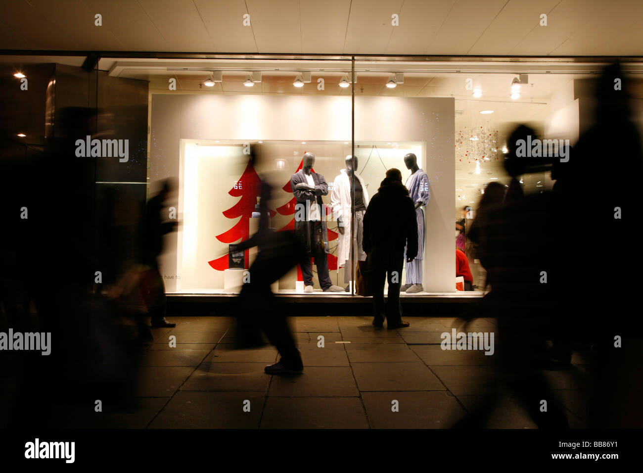 Christmas Shopper passando John Lewis department store in Oxford Street, London, Regno Unito Foto Stock