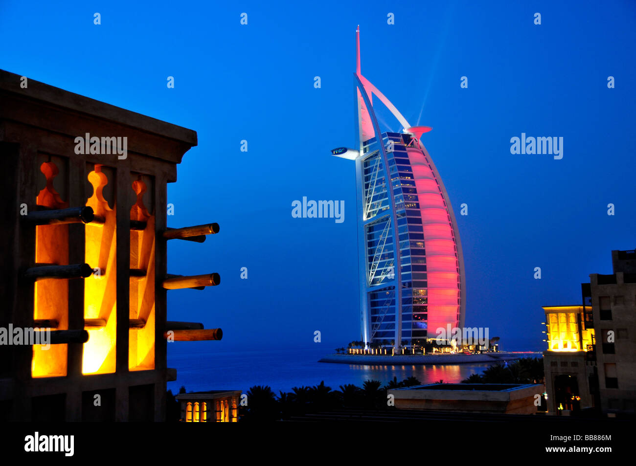 Stilizzata torre eolica del Madinat Jumeirah resort di fronte alla facciata illuminata delle sette stelle Burj al Arab, Ara Foto Stock