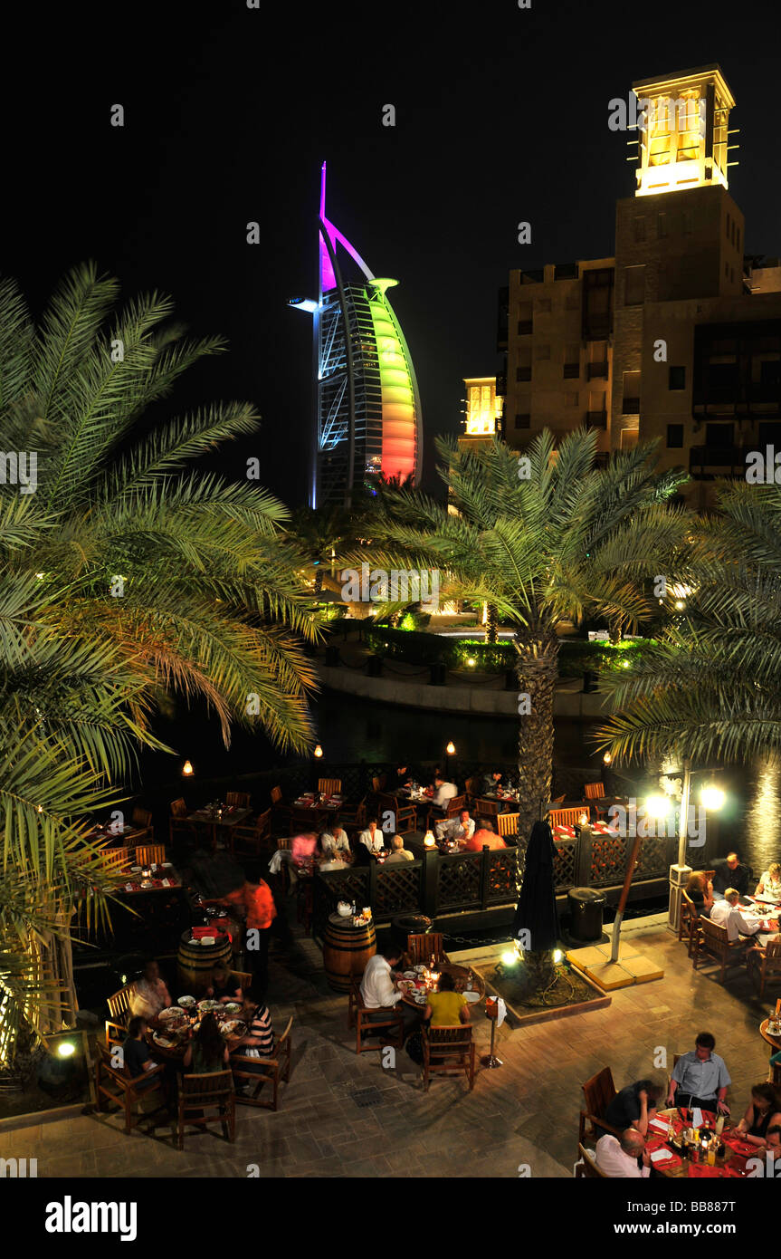 Il ristorante all'aperto presso il Madinat Jumeirah resort di fronte alla facciata illuminata delle sette stelle Burj al Arab, Ara Foto Stock