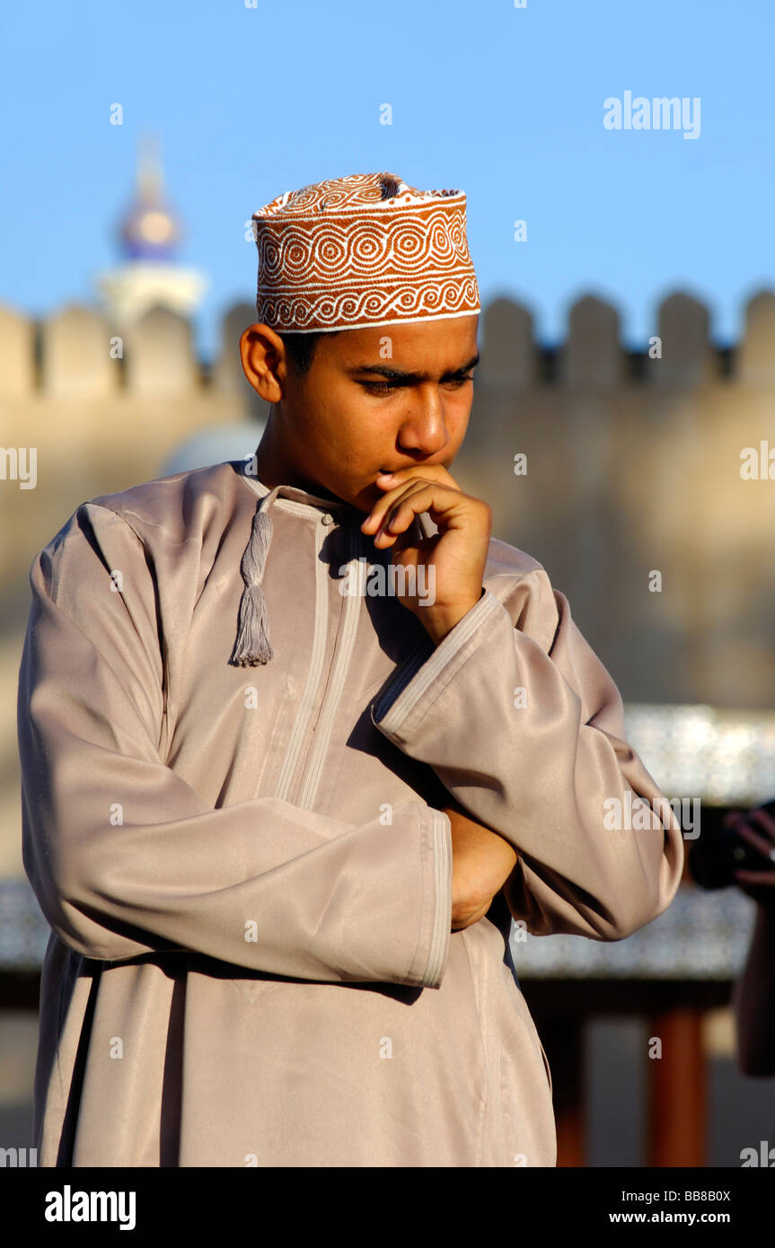 Omani ragazzo in costume nazionale dishdasha e un cappuccio kummah, perso nel pensiero, Nizwa, Sultanato di Oman Foto Stock