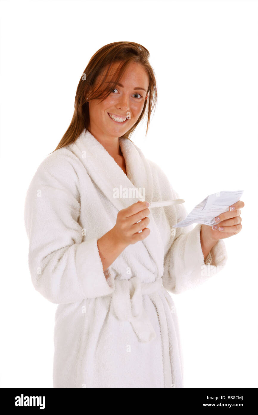 Femmina attraente tenendo un test di gravidanza e leggere le istruzioni cercando felice Foto Stock