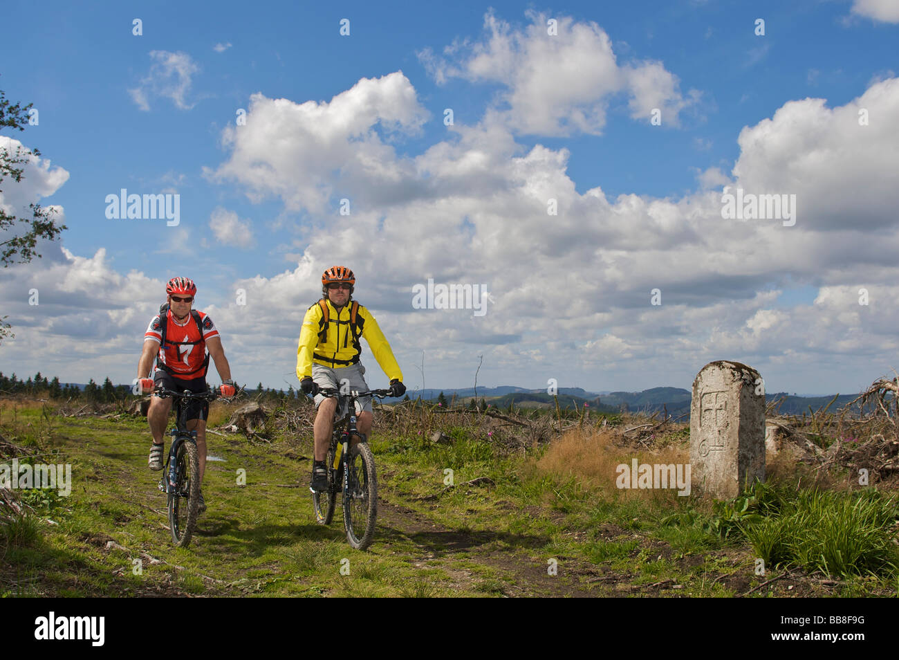 I motociclisti in mountain bike che passano accanto alla pietra di confine lungo il confine ridgeway, deforestato dal ciclone Kyrill, tra Nort Foto Stock