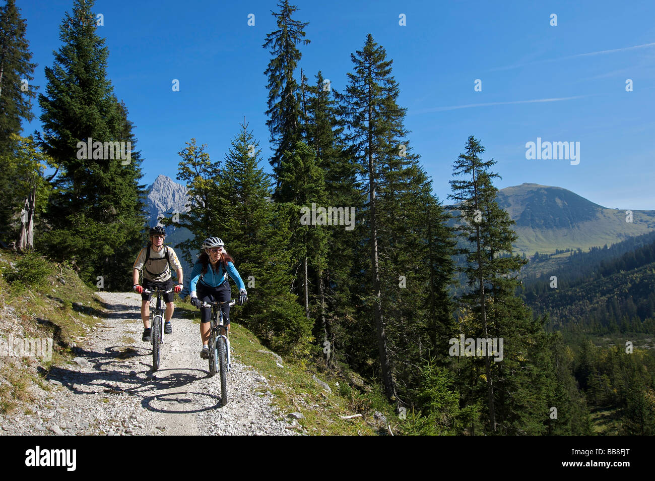 Mountainbike riders, maschio e femmina tra Karwendelhaus, alpine club house e Kleiner Ahornboden distretto forestale, Hinterri Foto Stock