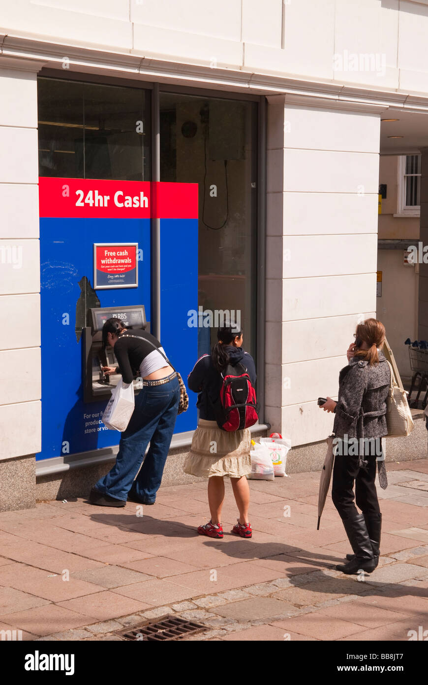 Persone queing fino a ritirare il denaro dalla Tesco bancomat foro nella parete speedbank atm in Norwich, Norfolk, Regno Unito Foto Stock