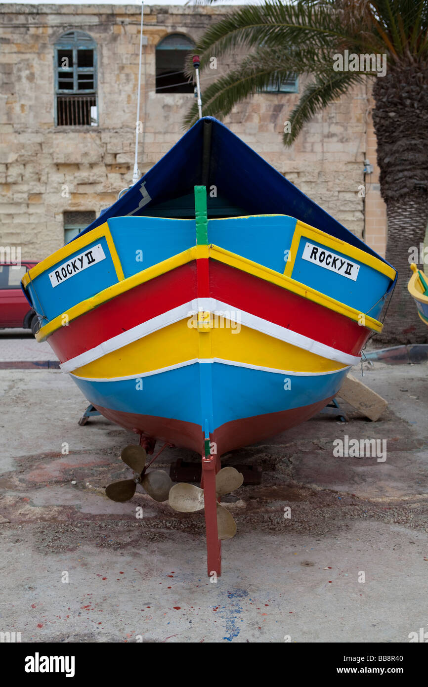 Maltese tradizionale barca da pesca, chiamato Luzzu, in piedi a terra per la manutenzione, porto di Marsaxlokk, Malta, Europa Foto Stock