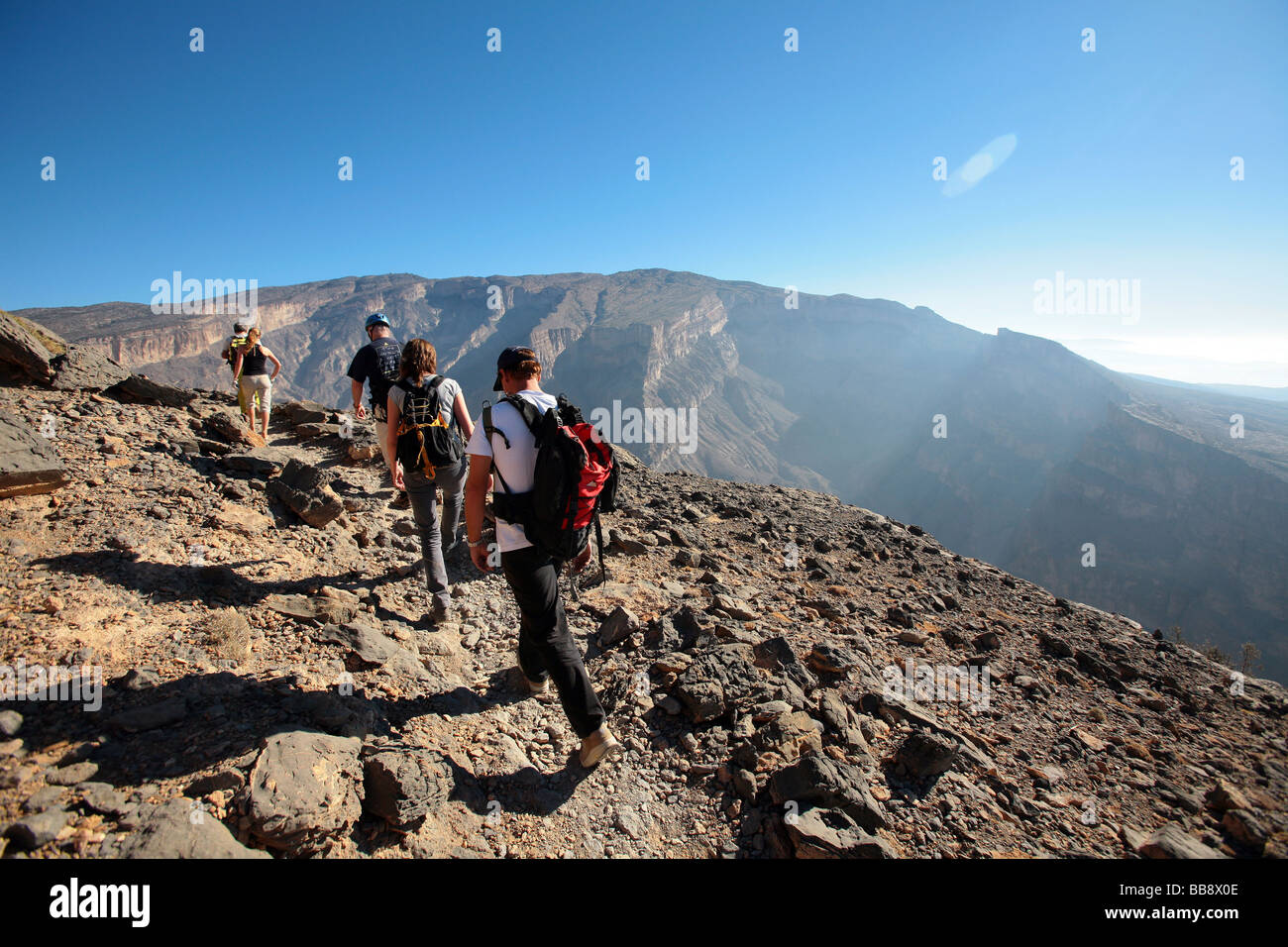 Un gruppo di turisti escursioni dal plateau superiore al fondo del Jebel Shams in Oman Foto Stock