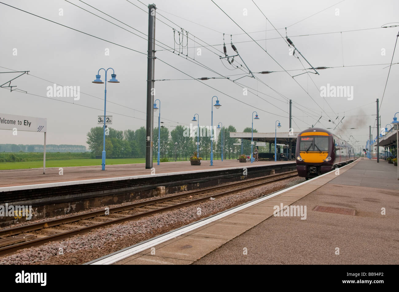 Treno locale arriva in corrispondenza di una stazione di provinciale nelle paludi di Cambridgeshire Foto Stock