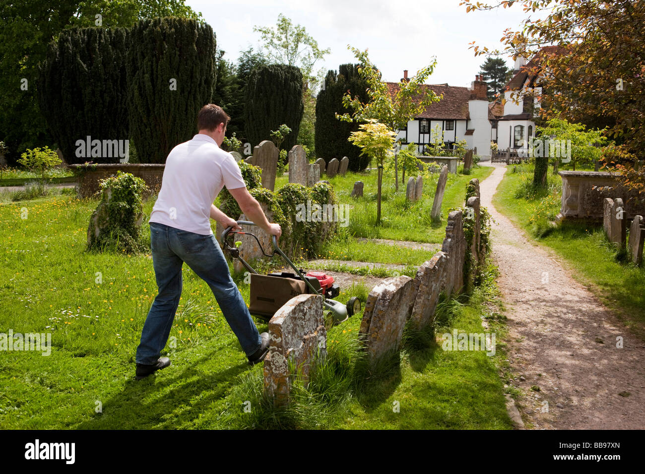 Inghilterra Berkshire Cookham Santa Trinità parrocchia sagrato uomo nel cimitero di falciatura erba con tosaerba Foto Stock