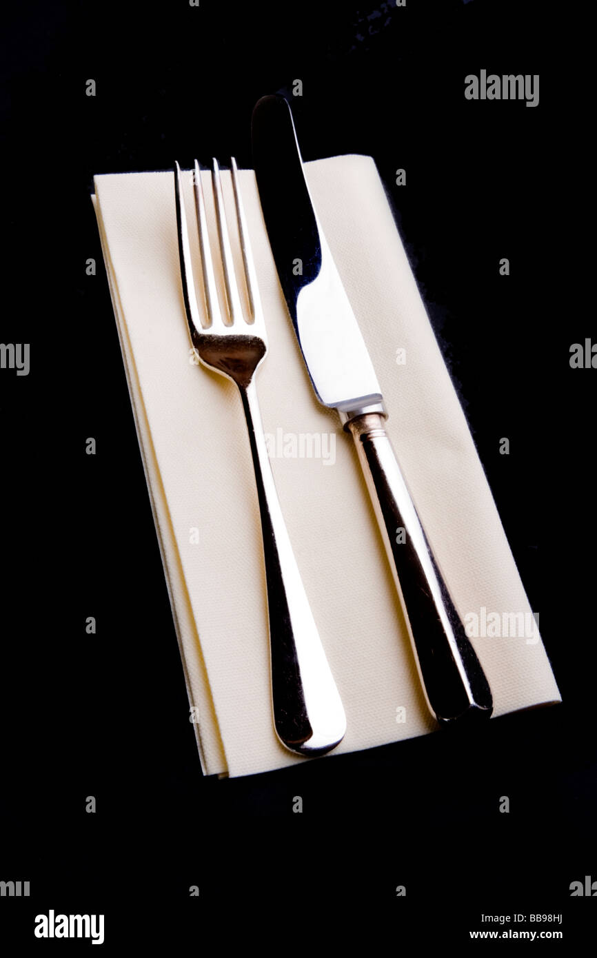 Placcato in argento coltello e forchetta su una crema di tabella di carta assorbente Foto Stock