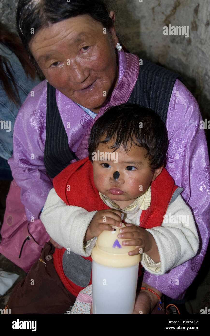 Ritratto verticale dei tibetani lady pellegrino tenendo una ragazza giovane con un dipinto di naso. I sieri Monestery, Lhasa in Tibet, in Cina. Foto Stock