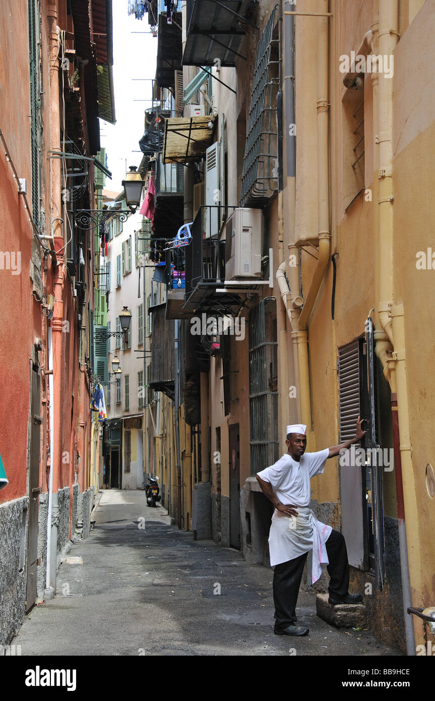 Uno chef prendendo una pausa al di fuori di un ristorante affollato nella vecchia Nizza Cote D'Azur, in Francia Foto Stock