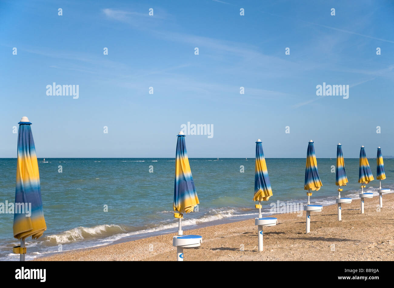 Blu e giallo listati ombrelloni in spiaggia Foto Stock