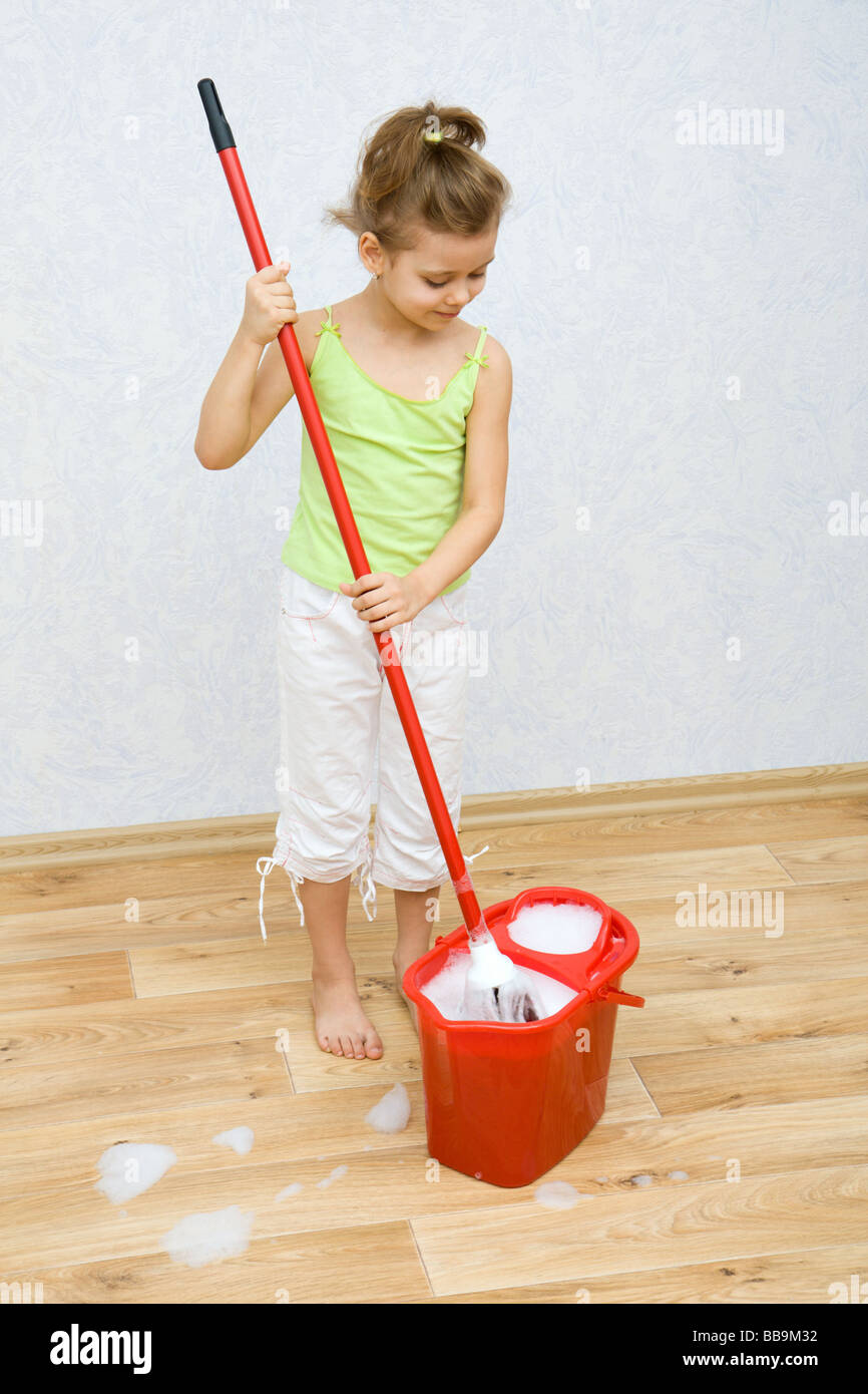 Bambina la pulizia del pavimento in camera Foto Stock