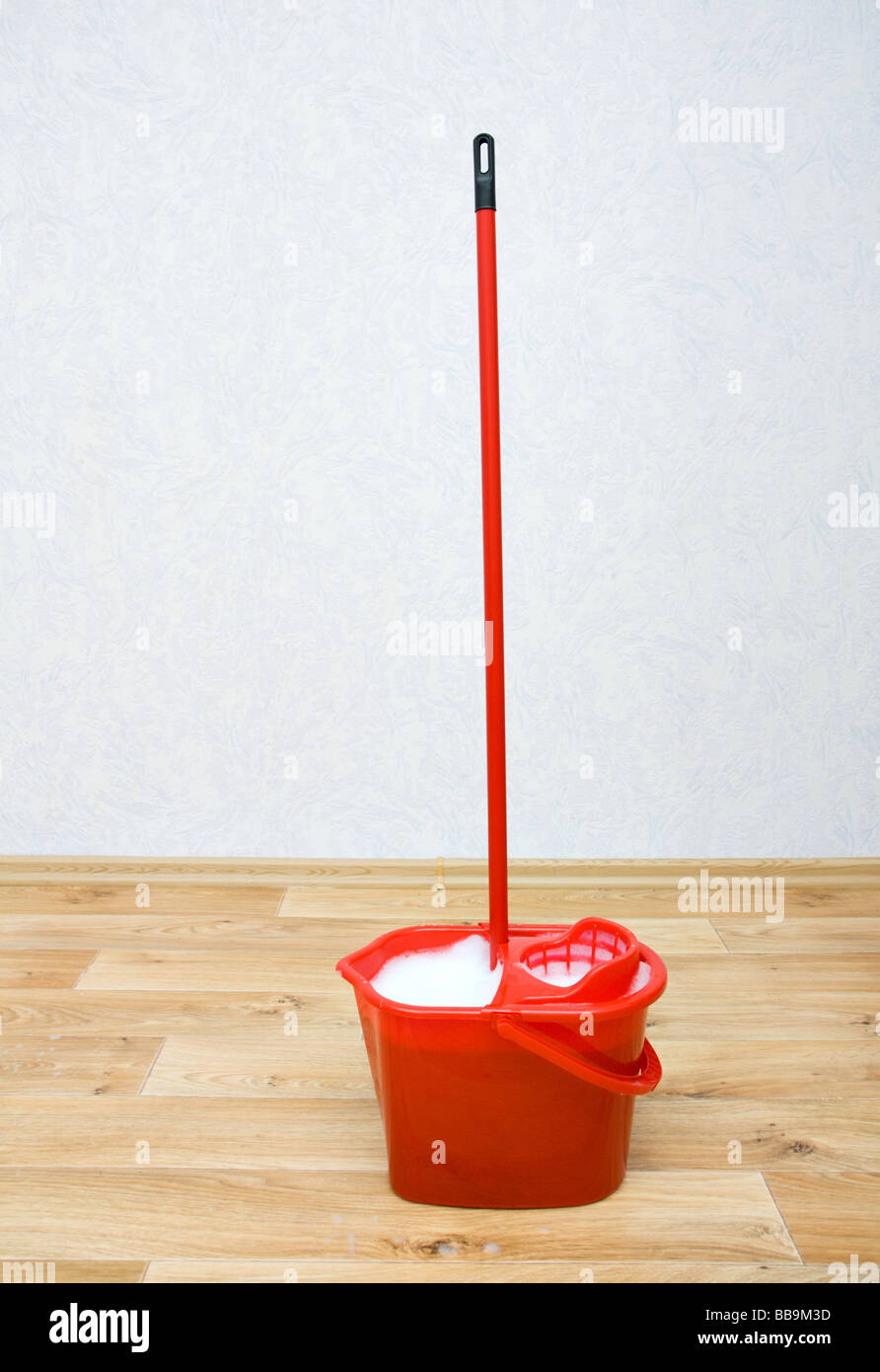 Un rosso mop in un secchio di plastica sul pavimento Foto Stock