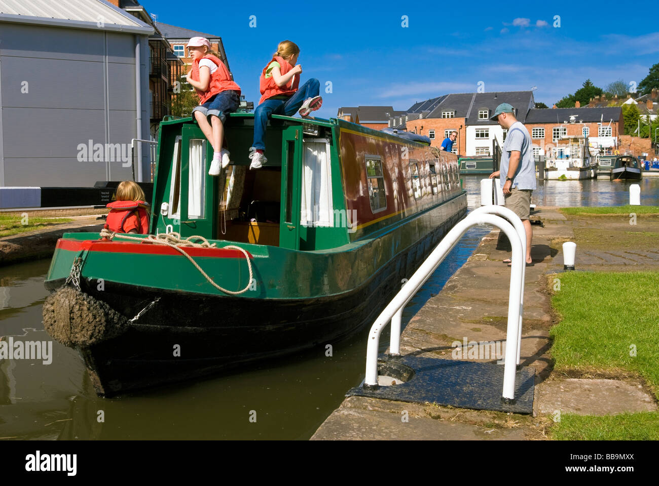 Barca stretta con tre ragazze in giubbotti di salvataggio, di entrare nel blocco del canale a bacinella Diglis, Worcester, Regno Unito. Canal Boat UK. Foto Stock