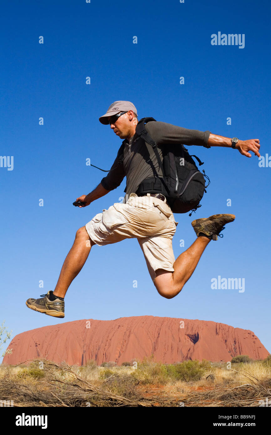 Backpacker saltando su Uluru (Ayers Rock). Uluru-Kata Tjuta National Park, il Territorio del Nord, l'AUSTRALIA Foto Stock