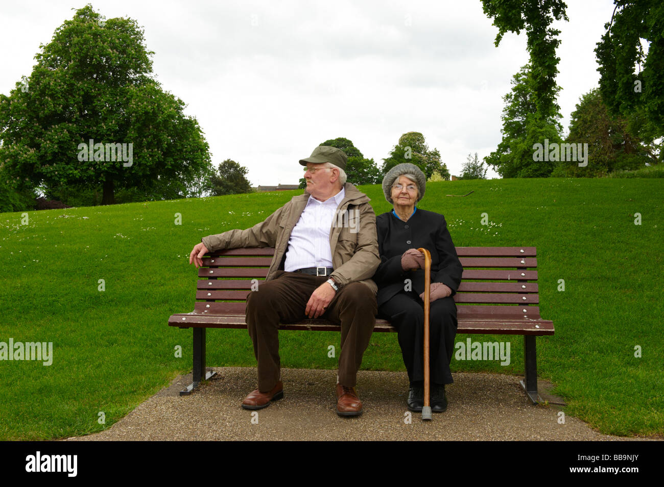 Anziana coppia sposata seduta su una panchina nel parco Foto Stock