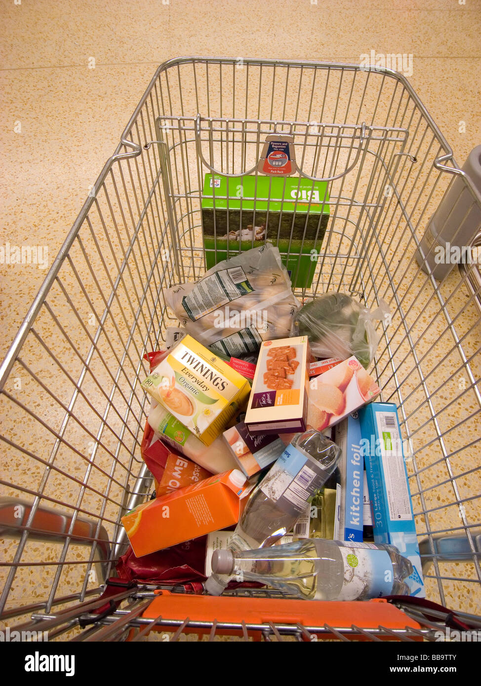 Un parzialmente riempito carrello per supermercati contenenti generi alimentari Foto Stock