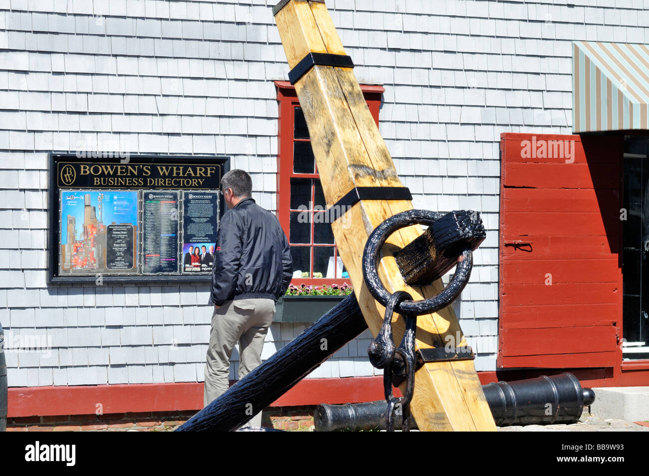 Uomo che guarda un segno di directory a Bowens Wharf area dello shopping con vecchie navi ancora in primo piano nel porto di Newport Rhode Island Foto Stock