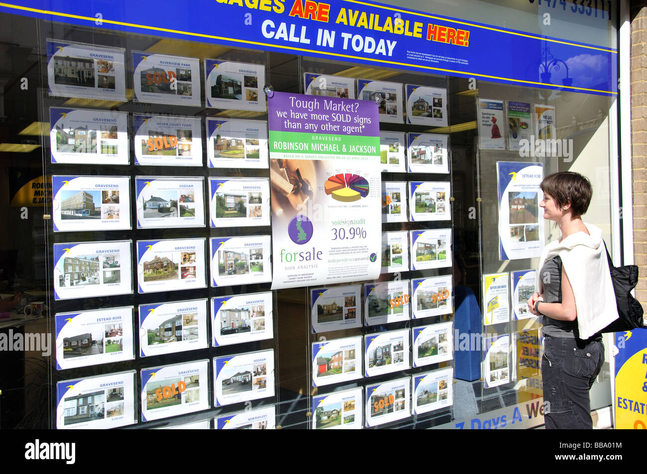 Donna che guarda in agente immobiliare della finestra, King Street, Anzio, England, Regno Unito Foto Stock