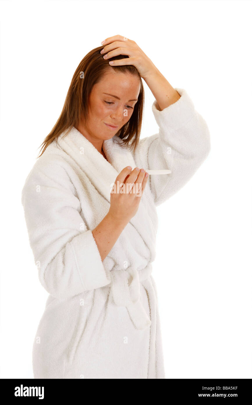 Femmina attraente guardando un test di gravidanza e guardando preoccupato Foto Stock