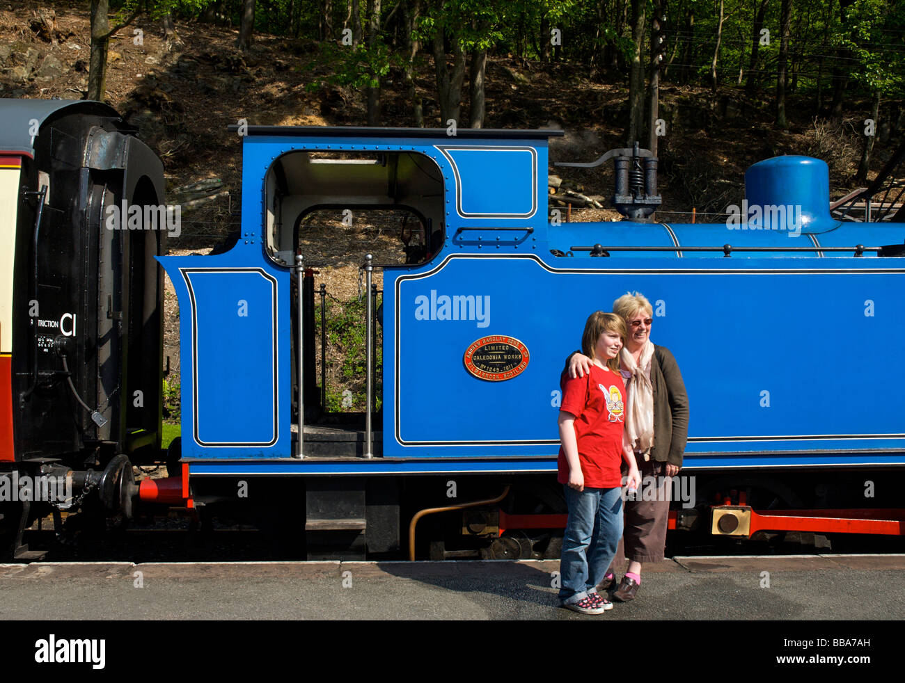 Donna e bambina in posa nella parte anteriore del motore, al lago & Haverthwaite ferroviarie, South Lakeland, Cumbria, England Regno Unito Foto Stock