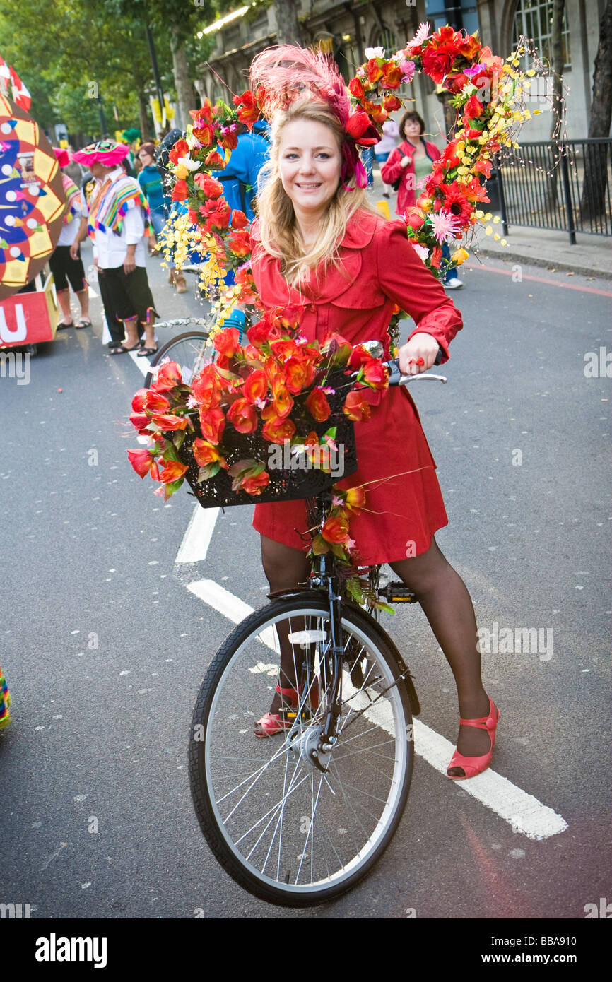 Un esecutore da Cyclodelic pone con noleggio biciclette decorate con fiori sul Tamigi Festival carnevale di notte a Londra REGNO UNITO Foto Stock