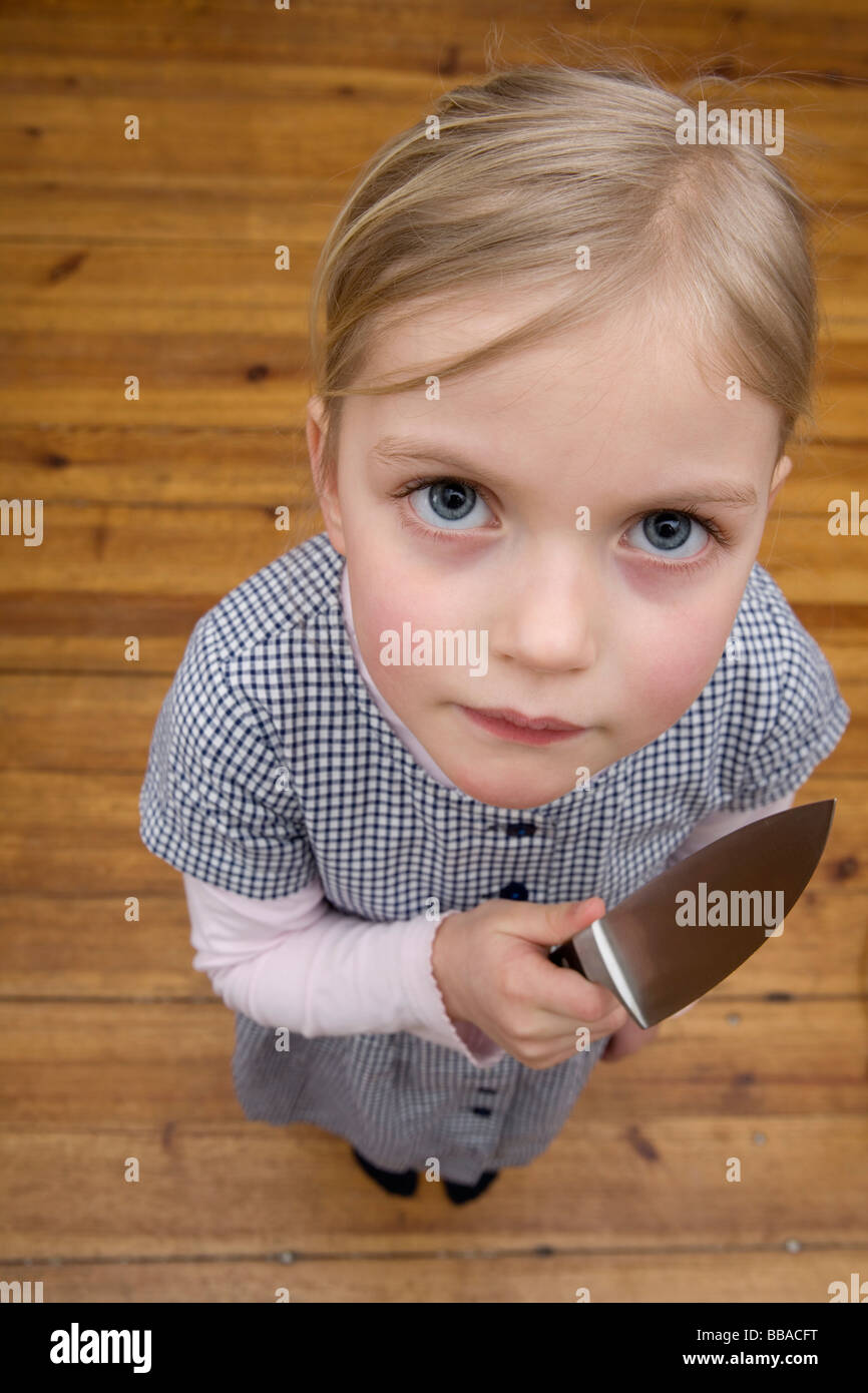 Una giovane ragazza con un coltello affilato minacciosamente Foto Stock