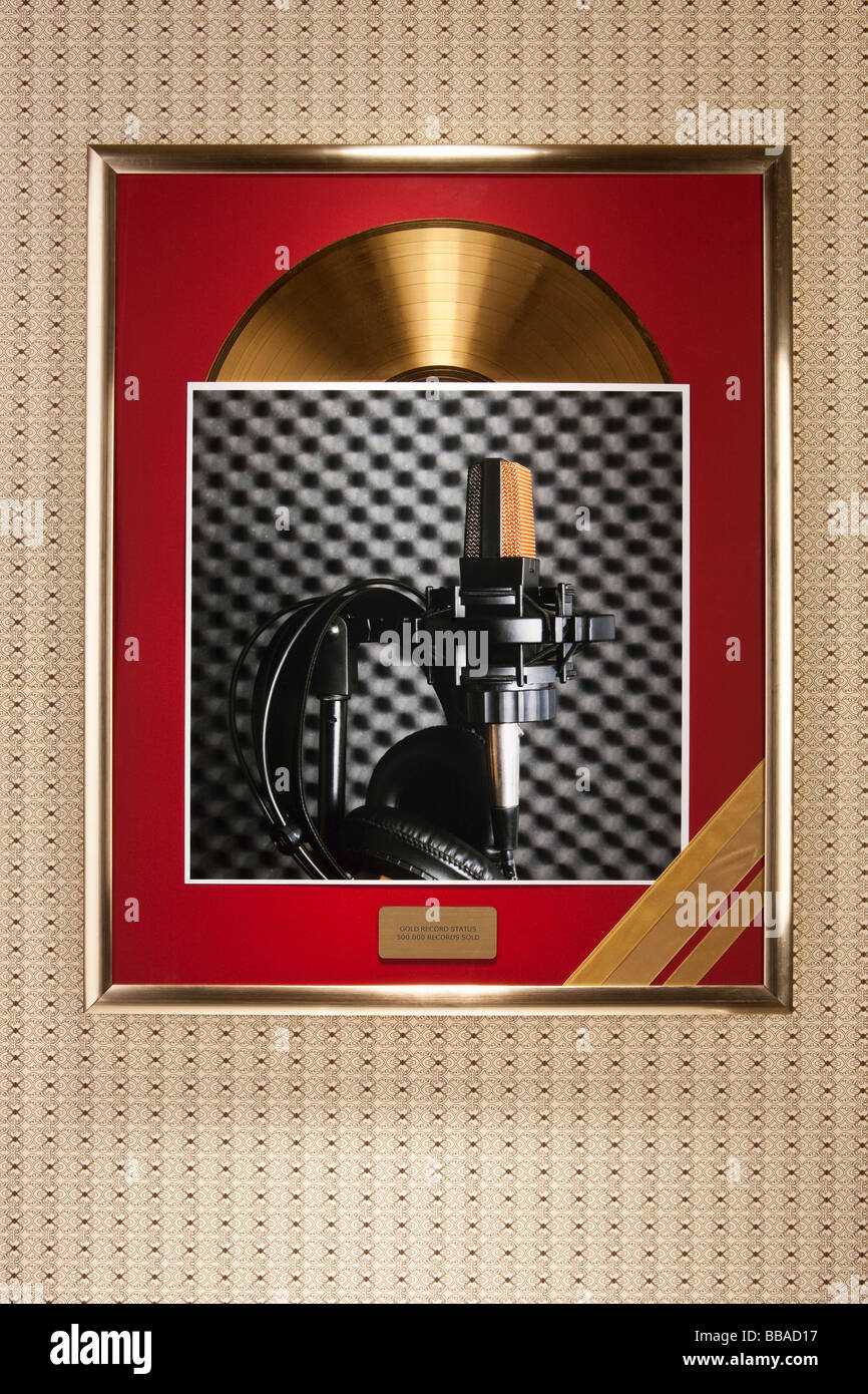 Una fotografia di un microfono e cuffie sulla parte superiore di una cornice per una registrazione d'oro Foto Stock