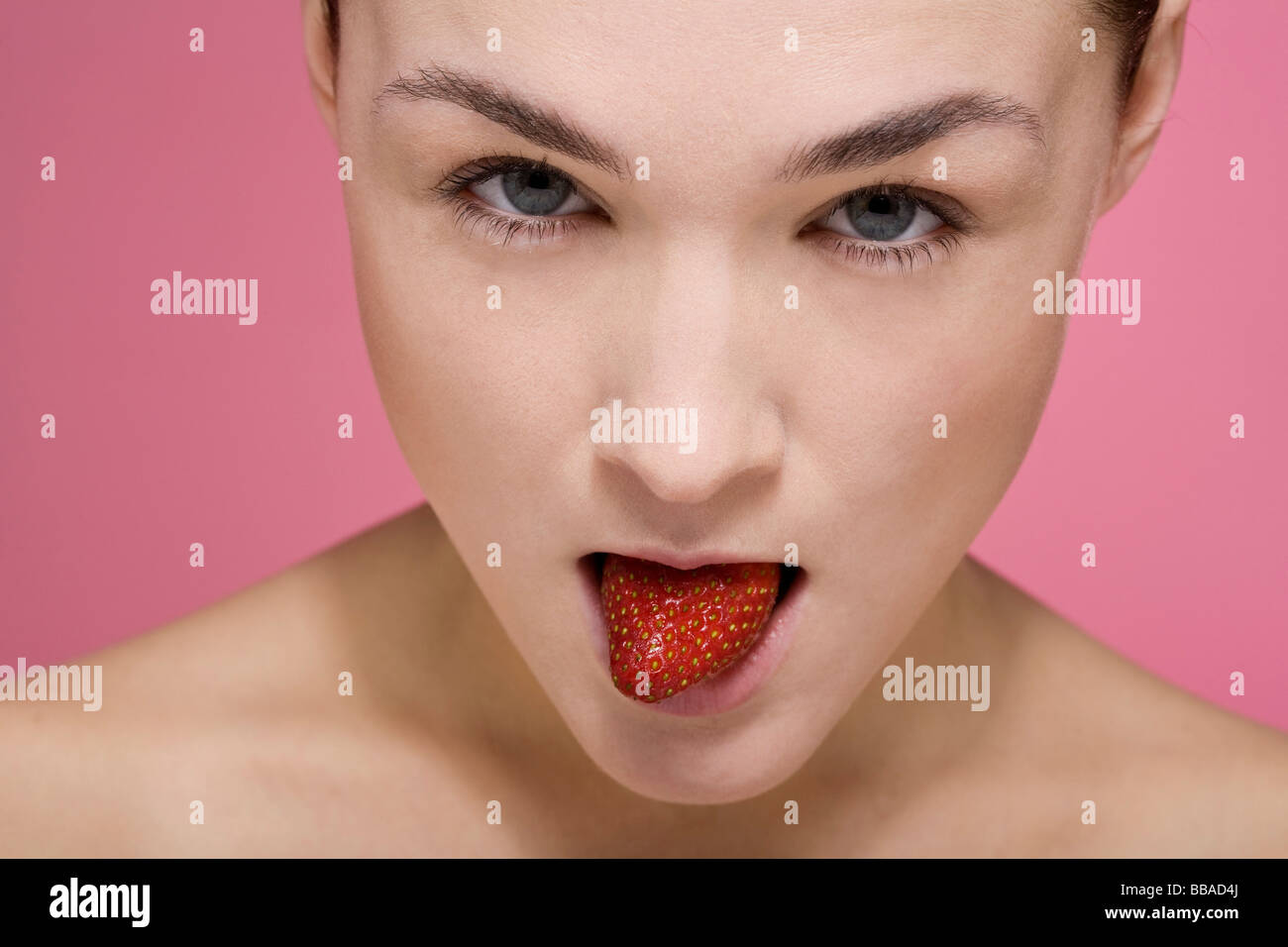 Una donna con una fragola in bocca Foto Stock