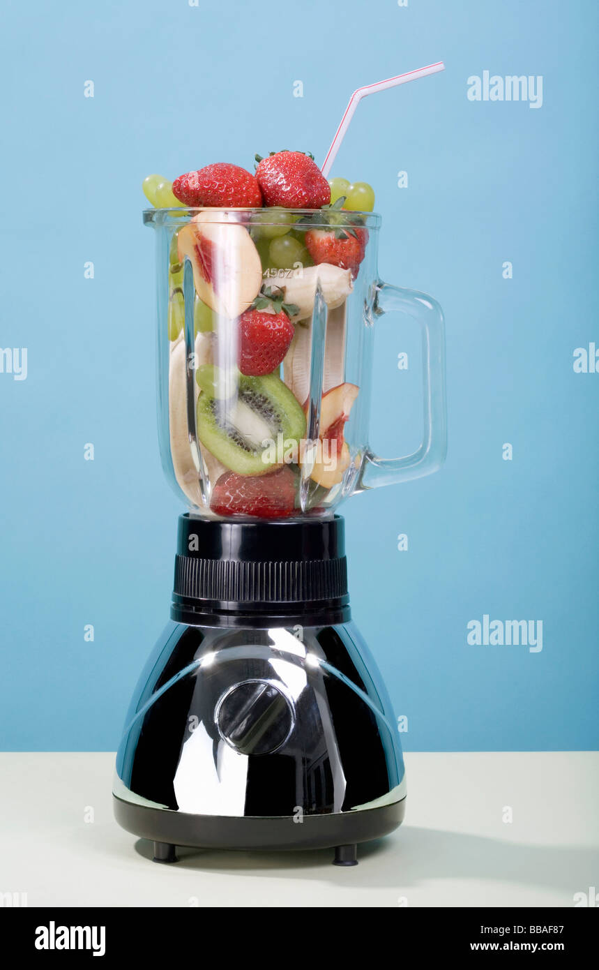 Un frullatore pieno di frutta con una cannuccia per bevande Foto Stock