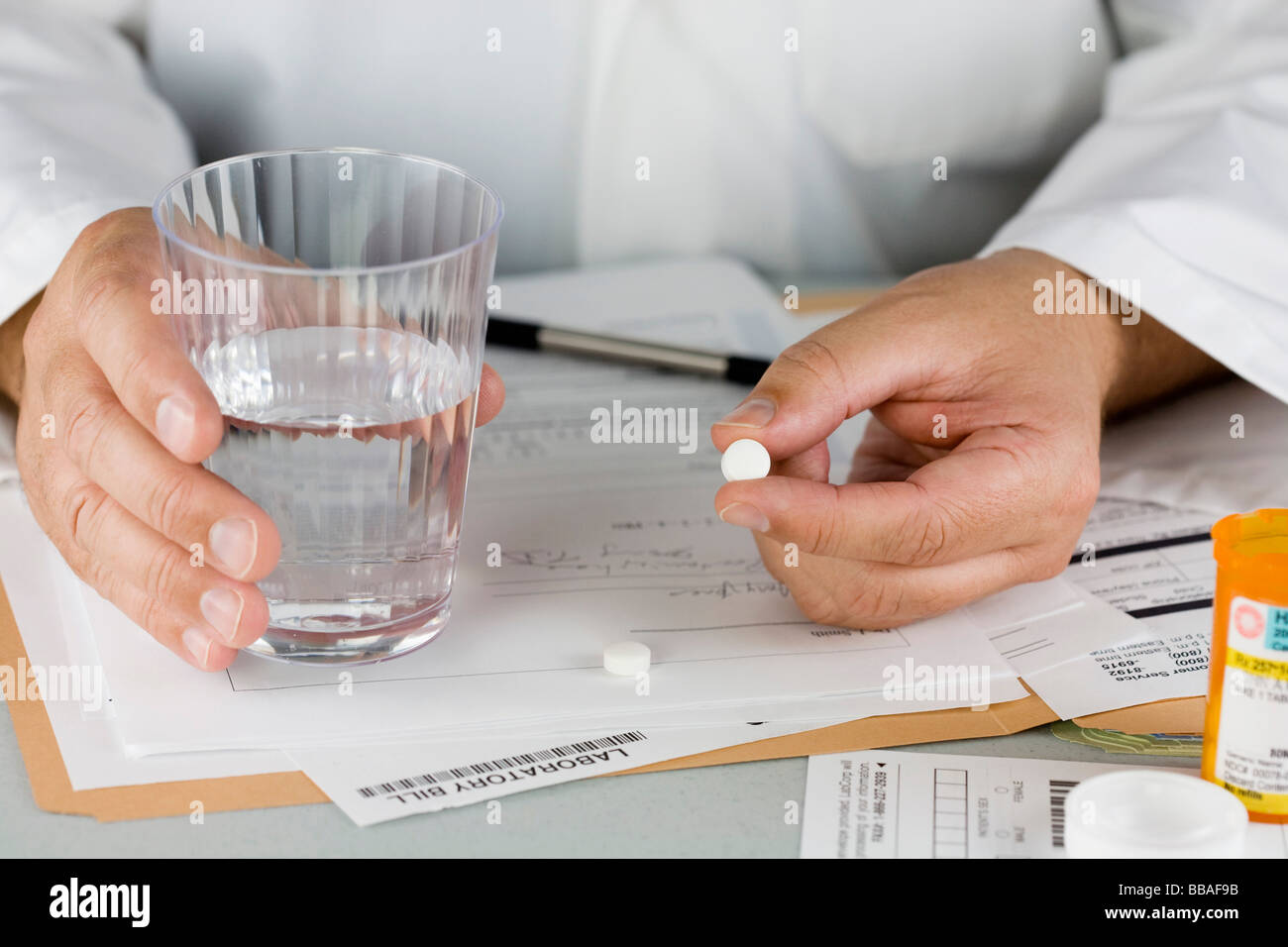 Un medico che offre una pillola e bicchiere di acqua Foto Stock