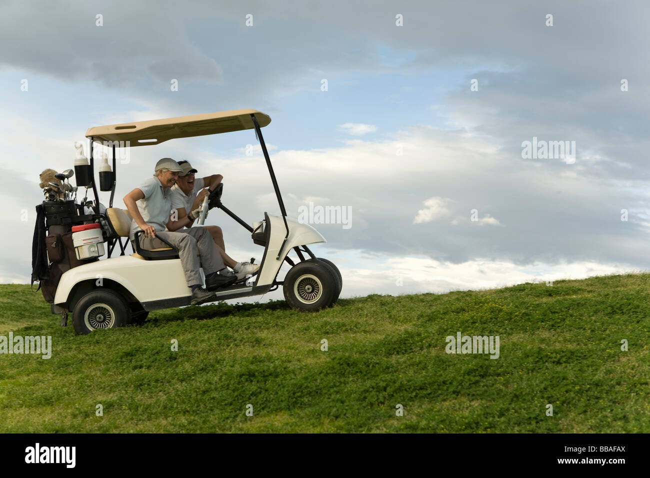 Due golfisti seduto in un golf cart e ridere Foto Stock