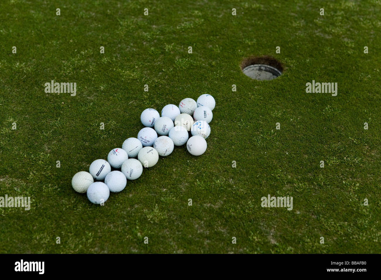 La freccia di palline da golf rivolto verso un foro su un putting green Foto Stock
