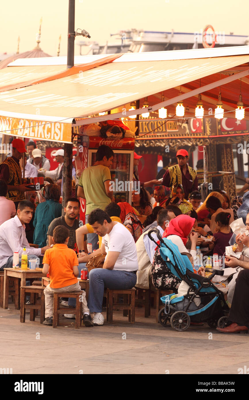Turchia Istanbul alimenti per pesci bancarelle con i clienti sul lungomare a Eminonu Foto Stock