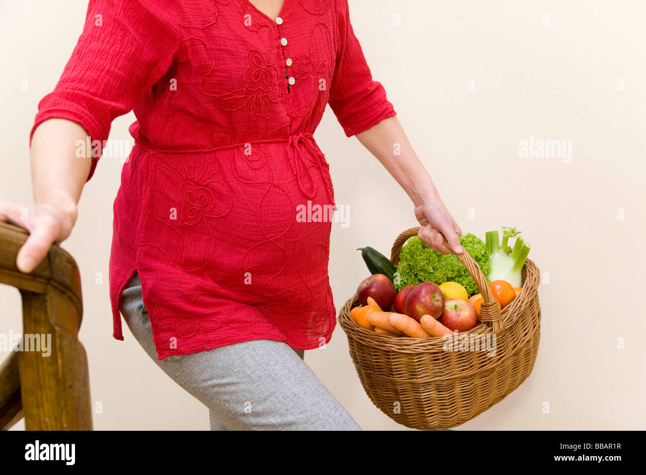 Donna incinta che porta un cesto di frutta Foto Stock