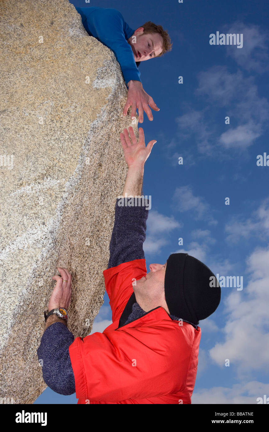 Scalatore offrendo la mano al compagno scalatore Foto Stock