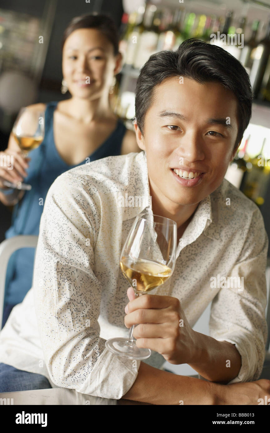 Uomo con un drink, appoggiata sul contatore, donna in background Foto Stock