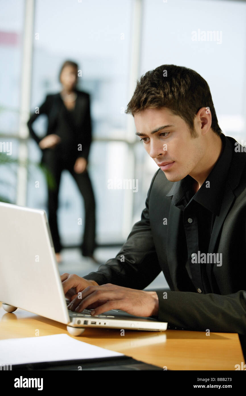 Executive maschio vestita di nero, utilizzando laptop Foto Stock