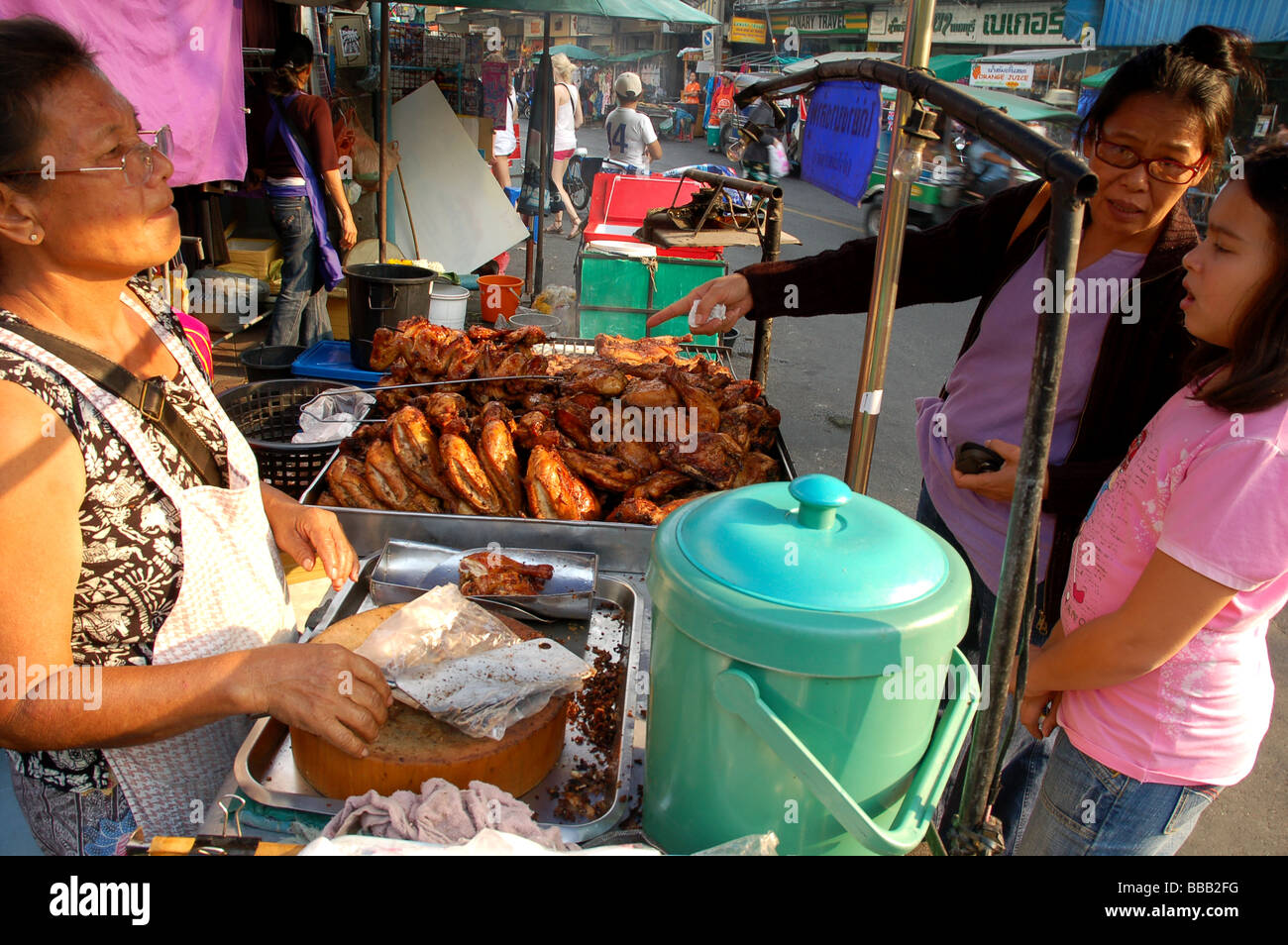Signora tailandese alla griglia di vendita le cosce di pollo in Khao San Road, Bangkok, Thailandia Foto Stock