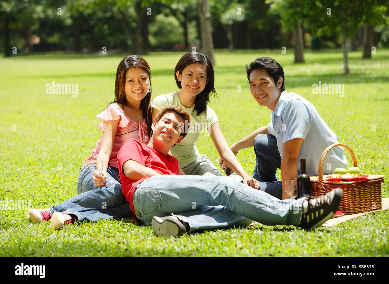 I giovani adulti seduti nel parco, guardando la fotocamera Foto Stock