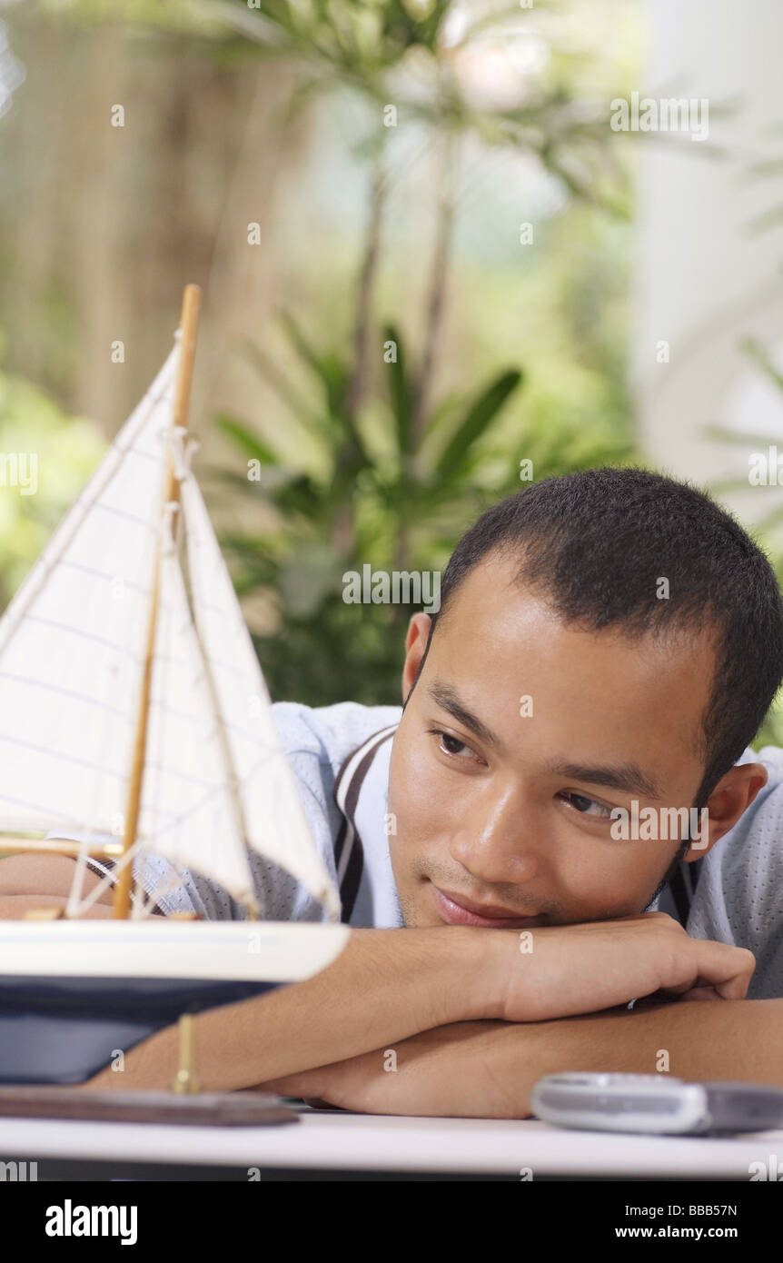 Uomo che guarda un modello in legno della barca, poggiando su bracci Foto Stock