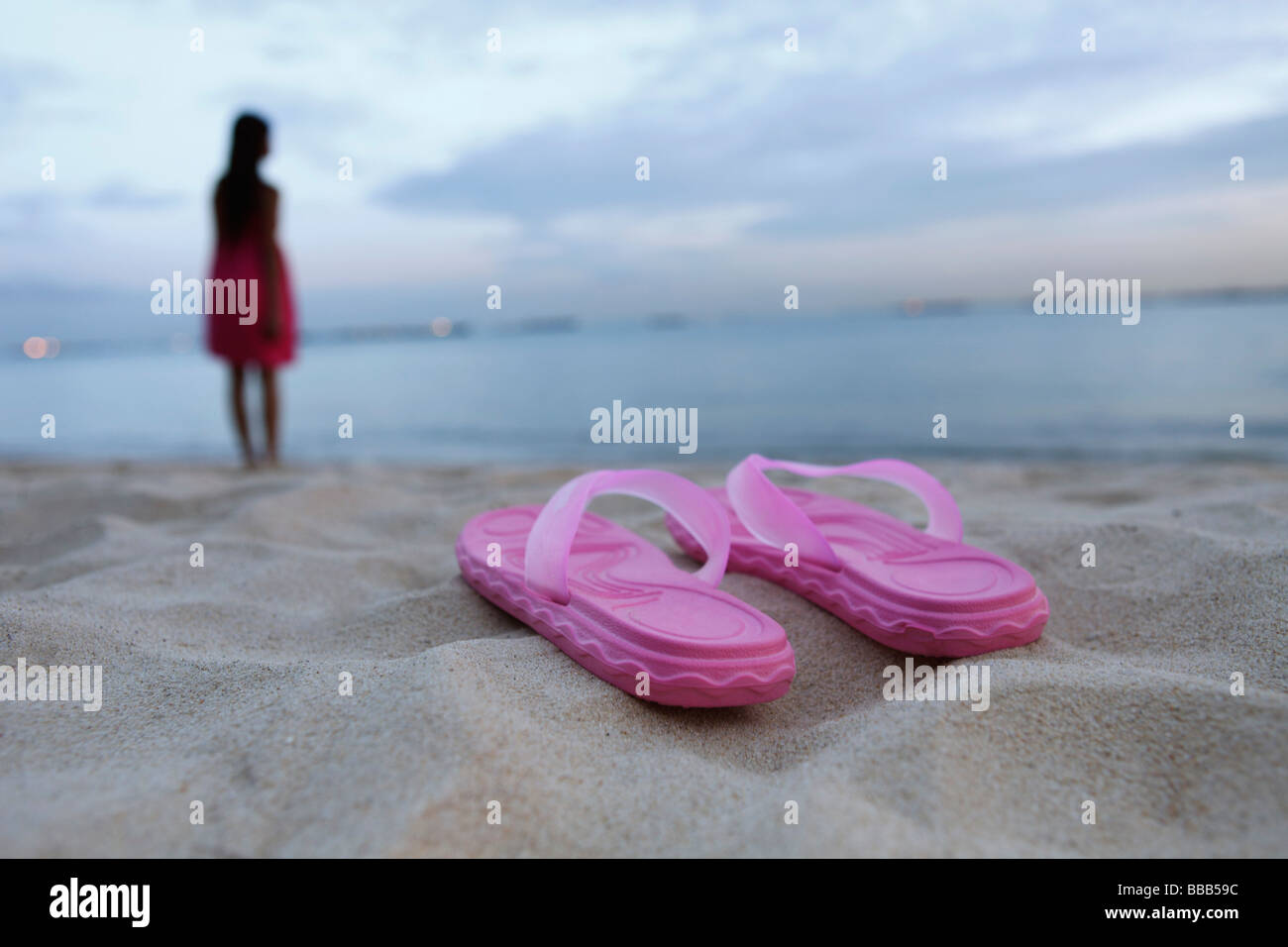 Sandali sulla spiaggia sabbiosa, donna in background Foto Stock